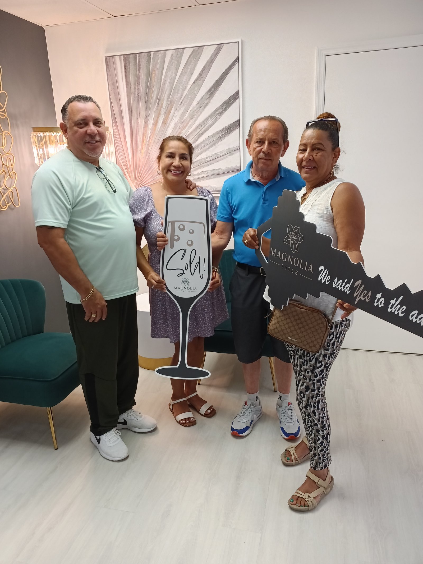 Closing celebration with clients holding a sold sign and an oversized key